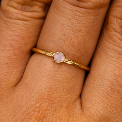 A solid 14k yellow gold Rose Quartz Gemstone Two Leaf Ring on a model's finger