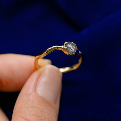 A model holding a round cabochon salt and pepper diamond waved engagement ring tilted to show details
