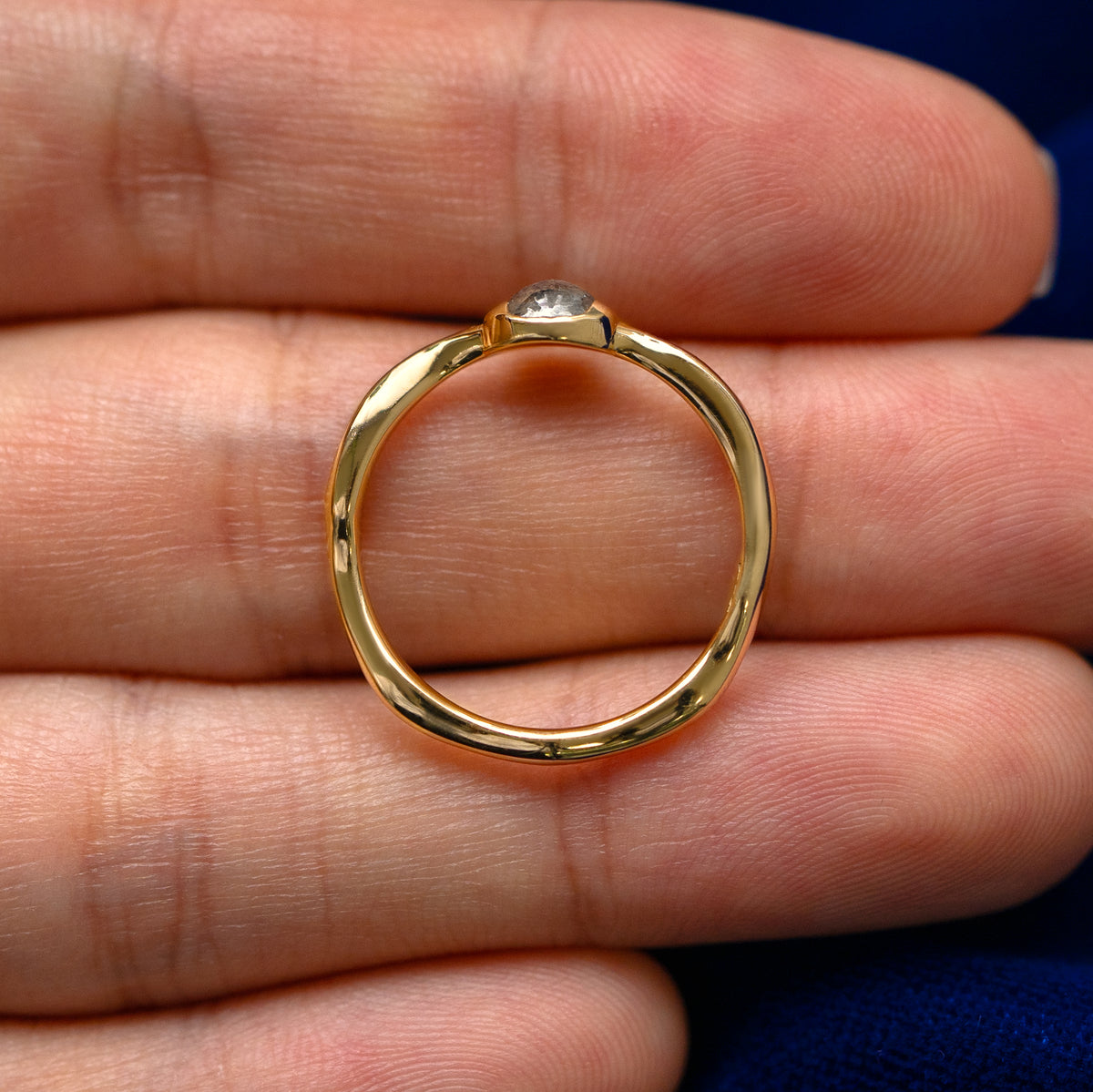 A yellow gold round salt and pepper diamond cabochon waved ring in a model's hand showing the thickness of the band