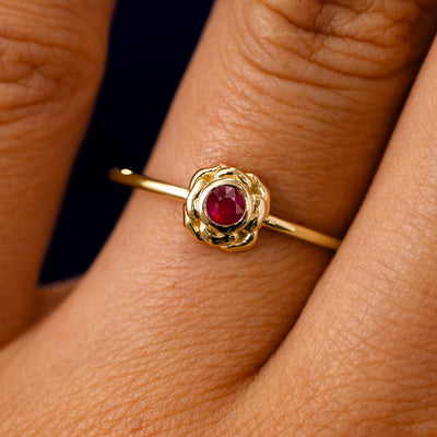 A solid 14k yellow gold Ruby Gemstone Flower Ring on a model's finger
