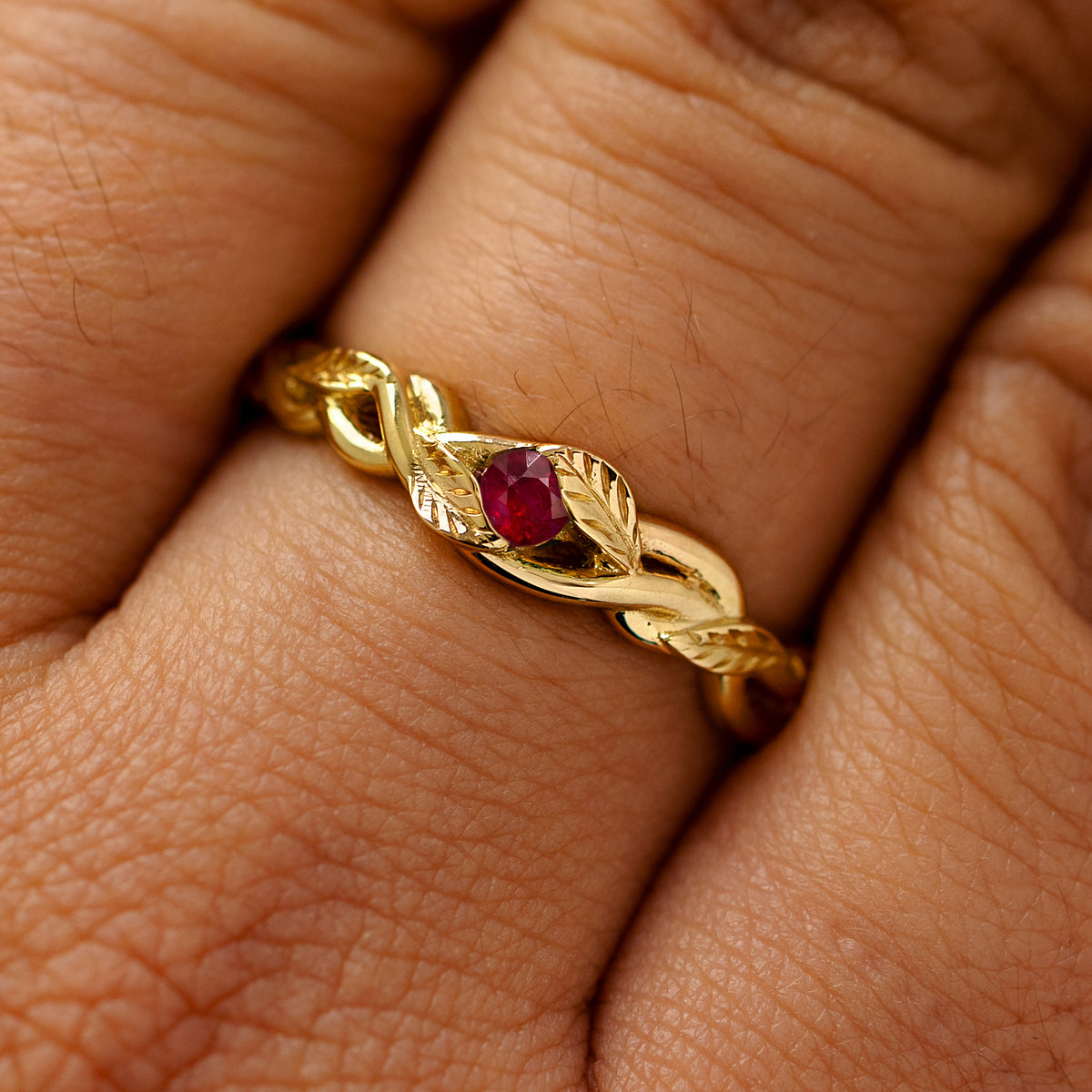 A solid 14k yellow gold ruby leaves and vines ring on a model's finger