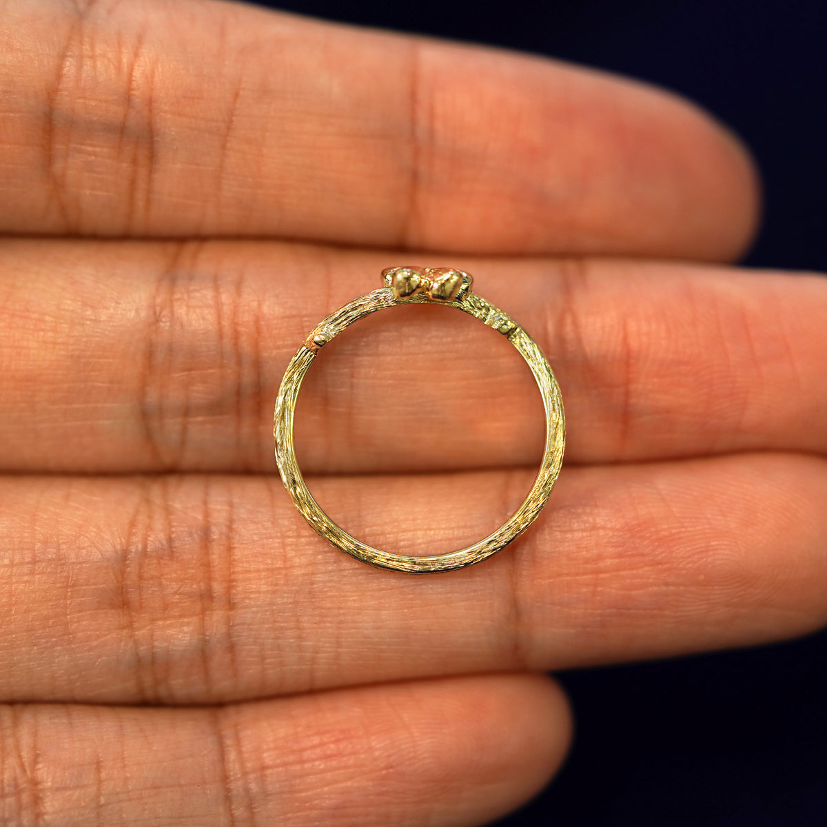 A yellow gold Sakura Ring in a model's hand showing the thickness of the band