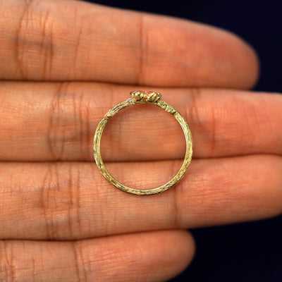 A yellow gold Sakura Ring in a model's hand showing the thickness of the band