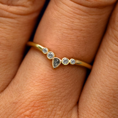 Close up view of a model's fingers wearing a 14k yellow gold Chevron Tiara Salt and Pepper Diamond Band