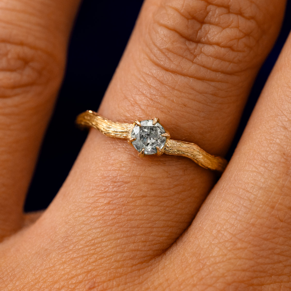 A solid 14k yellow gold Salt and Pepper Diamond Waved Branch Ring on a model's finger