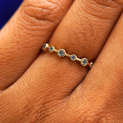 Close up view of a model's fingers wearing a 14k yellow gold Infinity Salt and Pepper Diamond Ring