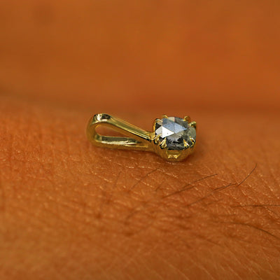 A 14k yellow gold Salt and Pepper Diamond Charm for chain resting on the back of a model's hand