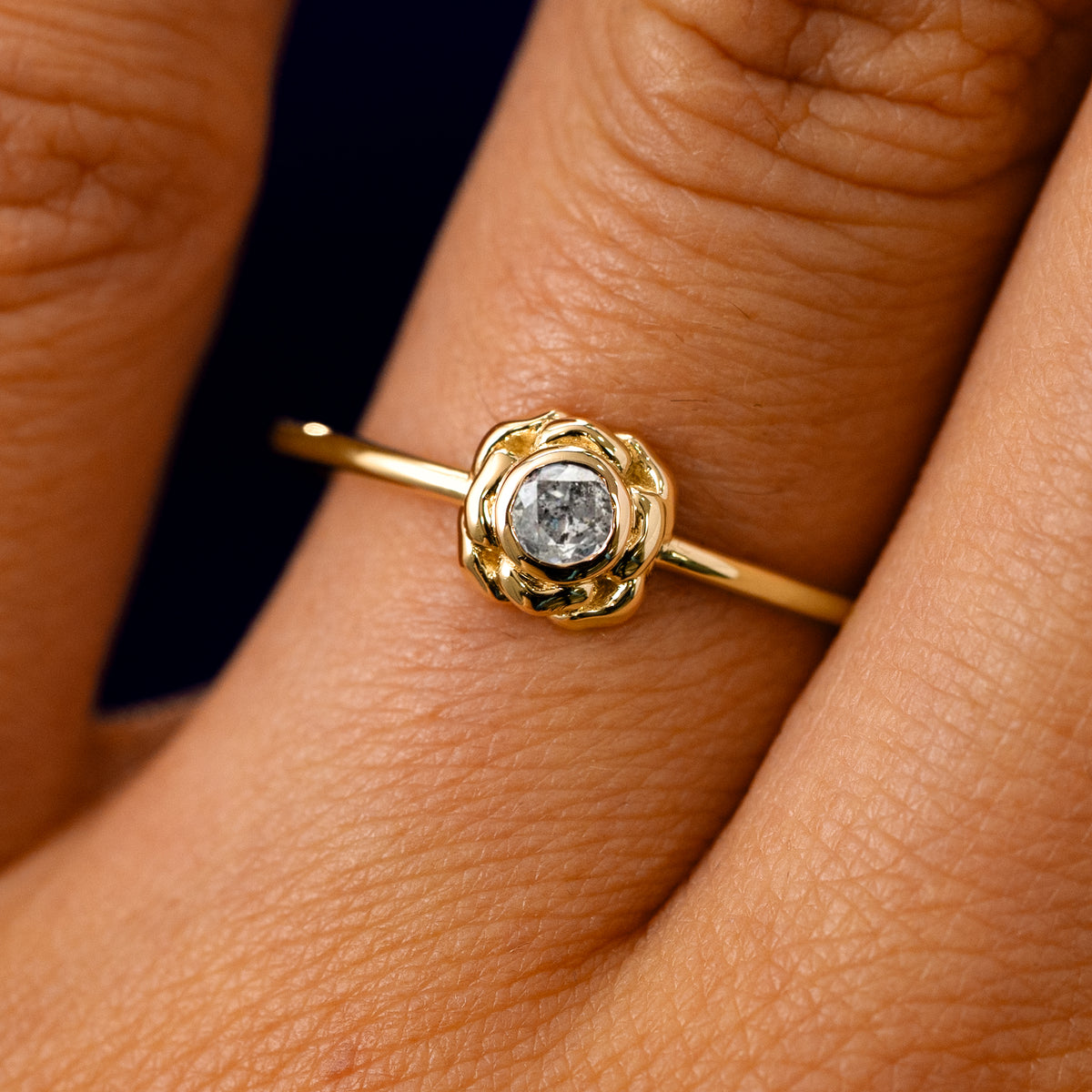 A solid 14k yellow gold Salt and Pepper Diamond Flower Ring on a model's finger