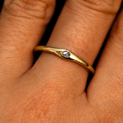 A 14k yellow gold Flush Set Oval Salt and Pepper Diamond Ring on a model's finger
