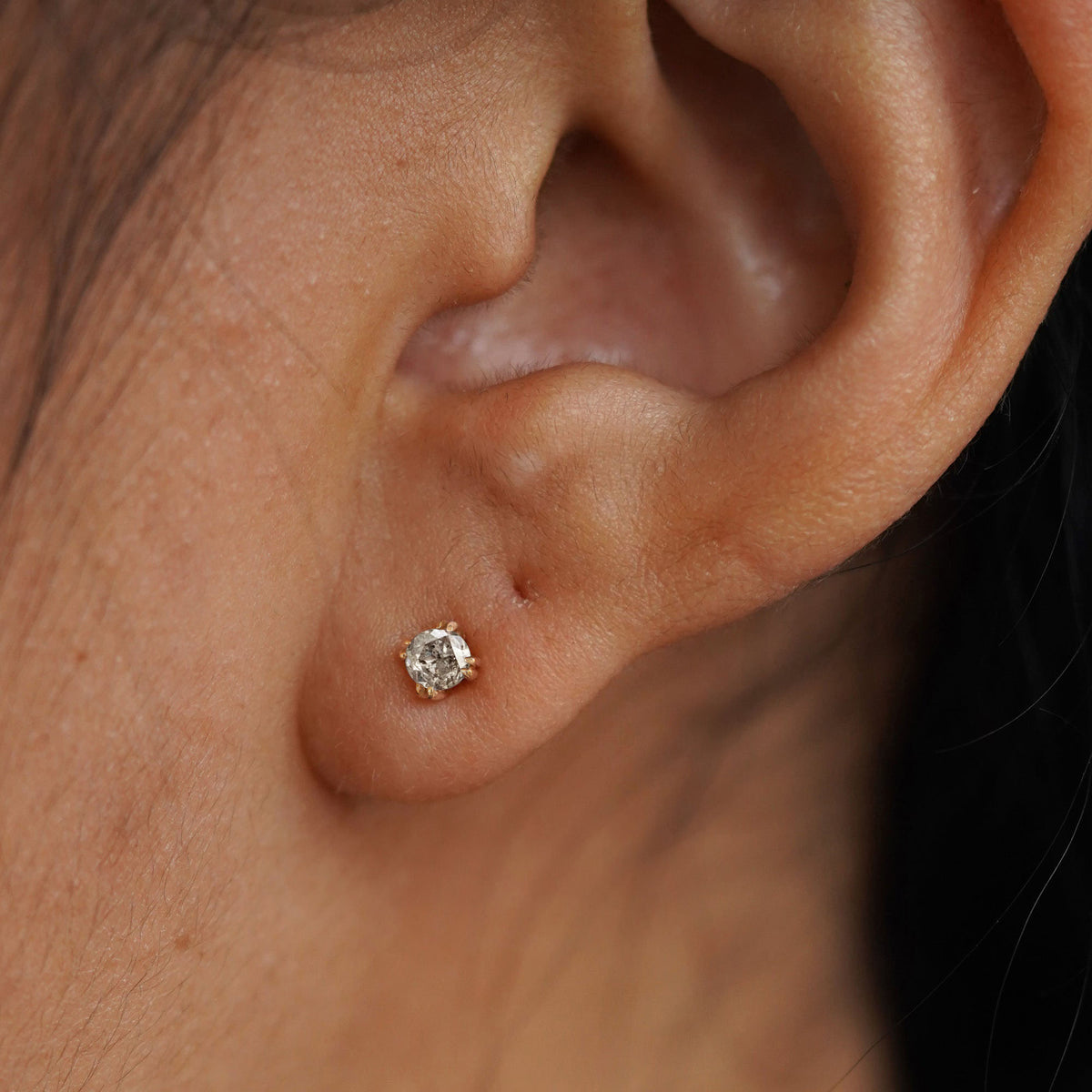 A model's ear wearing a 14k yellow gold Salt and Pepper Diamond Earring