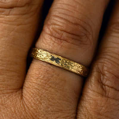 A salt and pepper baguette diamond raw band on a models finger