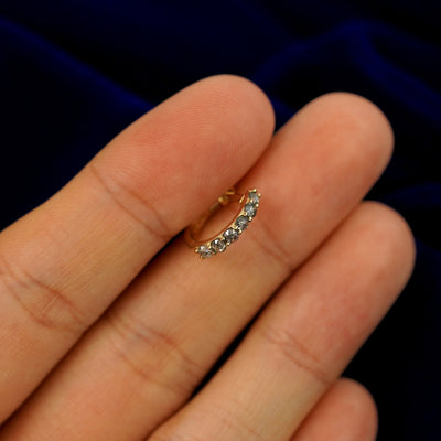 A small rose cut salt and pepper diamond huggie hoop earring between a model's fingers to show the gems