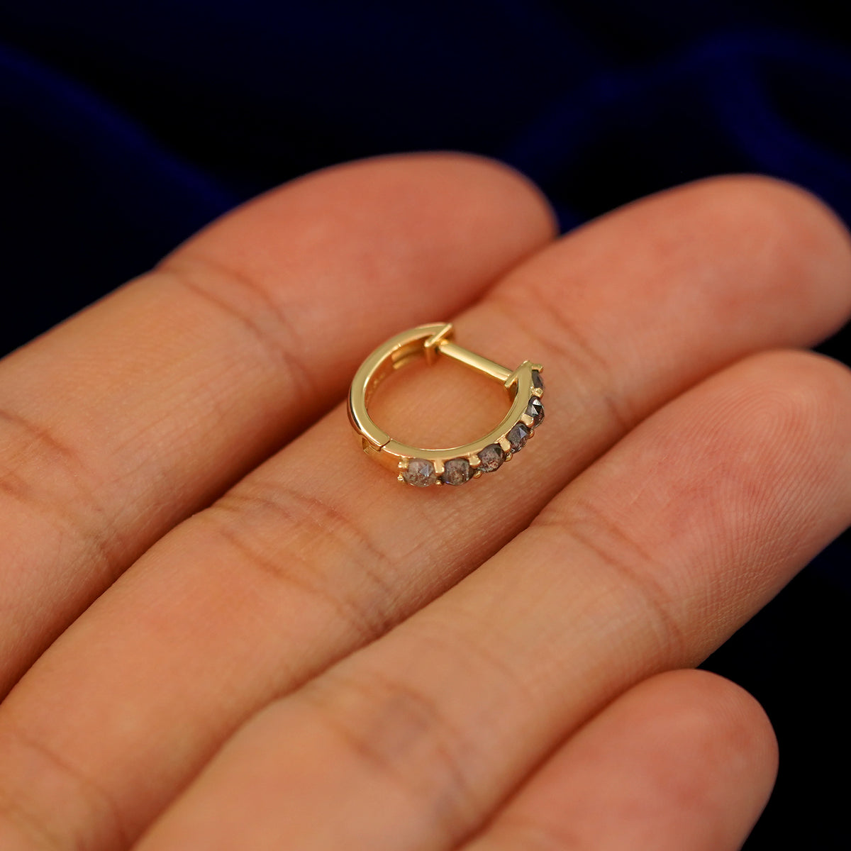 A small rose cut salt and pepper diamond huggie hoop earring on a models fingers