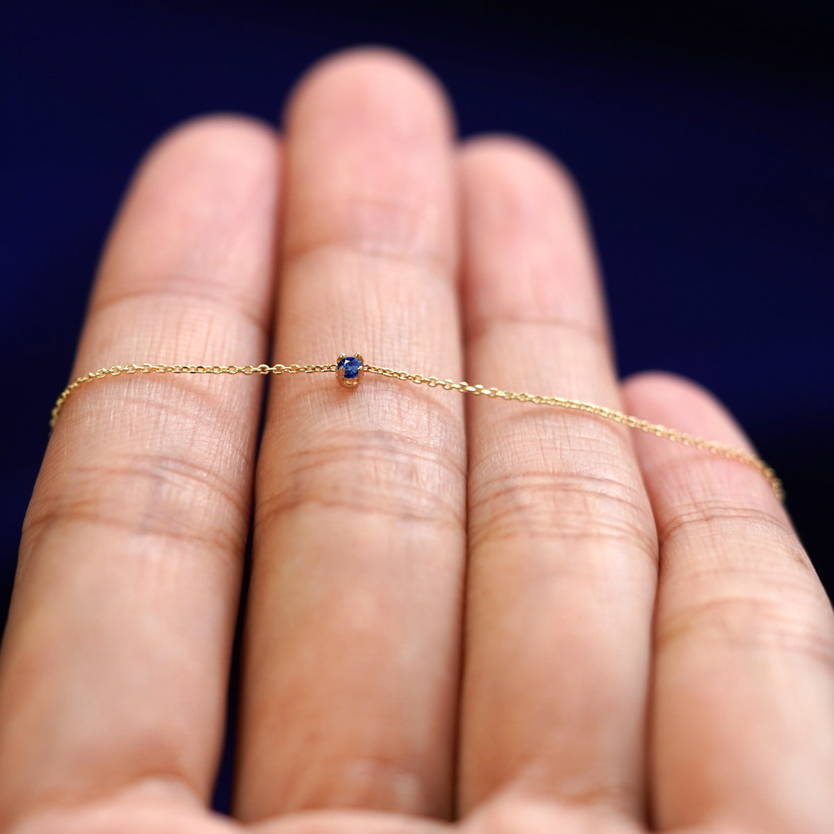 A yellow gold sapphire Gemstone Cable Necklace resting on a model's fingers