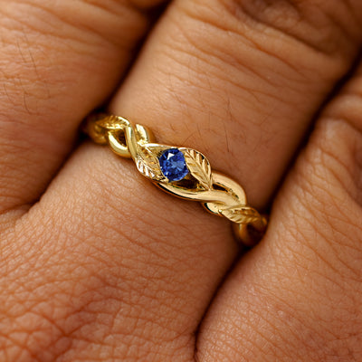 A solid 14k yellow gold sapphire leaves and vines ring on a model's finger