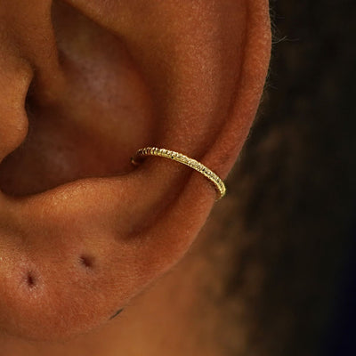 Close up view of a model's ear wearing a 14k solid yellow gold Shimmer Line Cuff