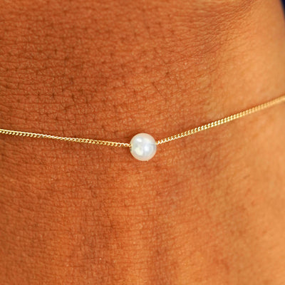 Close up view of a model's wrist wearing a yellow gold Pearl Slide Bracelet with a 4mm pearl