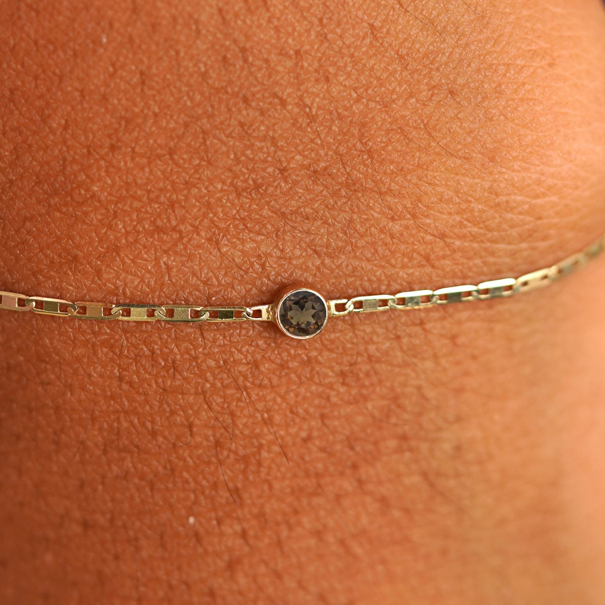 Close up view of a models wrist wearing 14k yellow gold Smoky Quartz Bracelet