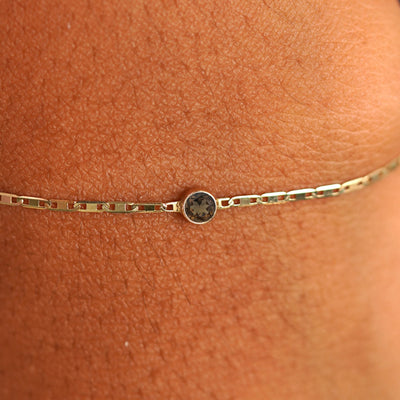 Close up view of a models wrist wearing 14k yellow gold Smoky Quartz Bracelet
