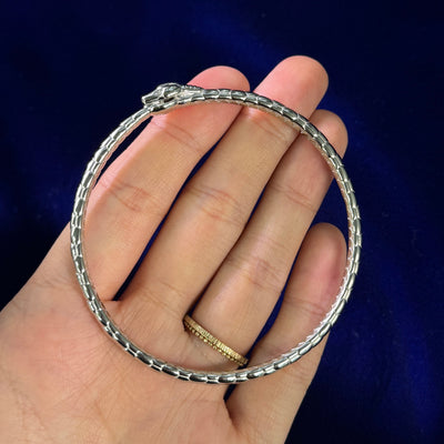 A model holding a 950 platinum snake bangle bracelet in the palm of their hand to show the side detail