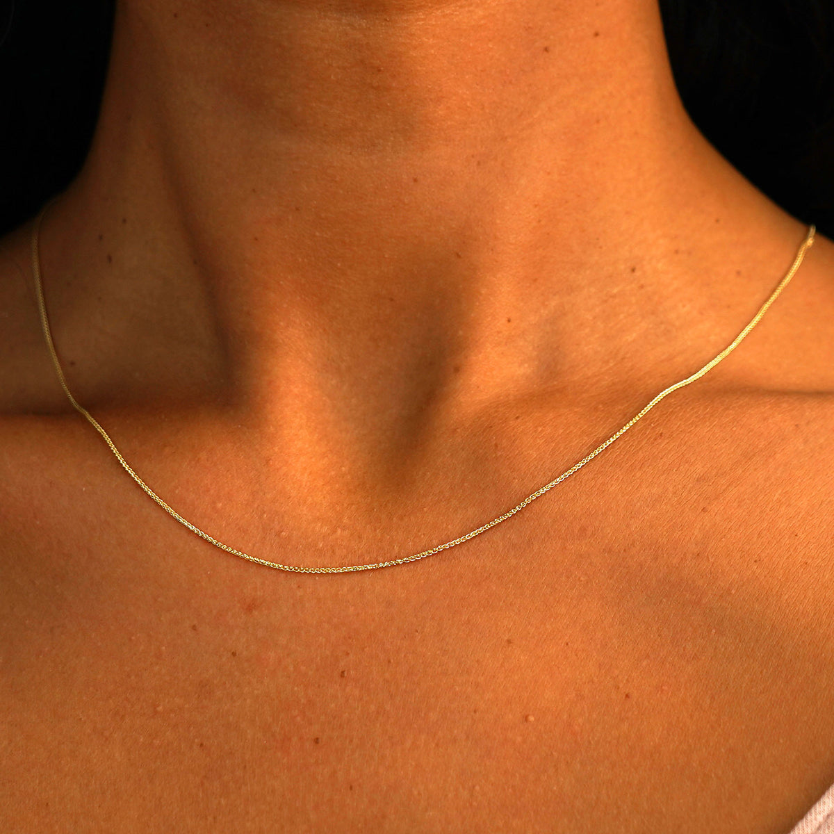 A model's neck wearing a solid 14k yellow gold Wheat Chain
