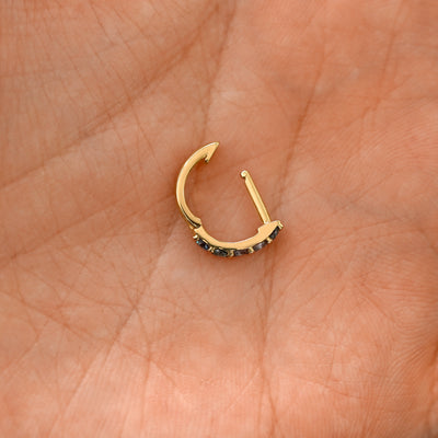 An open Alexandrite huggie hoop laying in a models palm