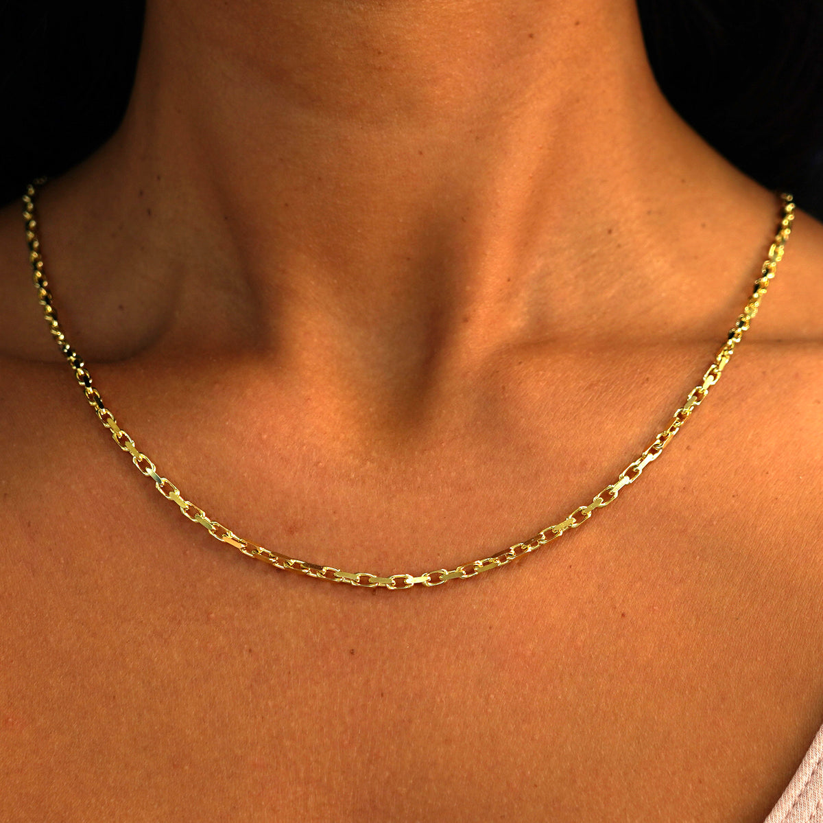 A model's neck wearing a solid 14k yellow gold Anchor Chain