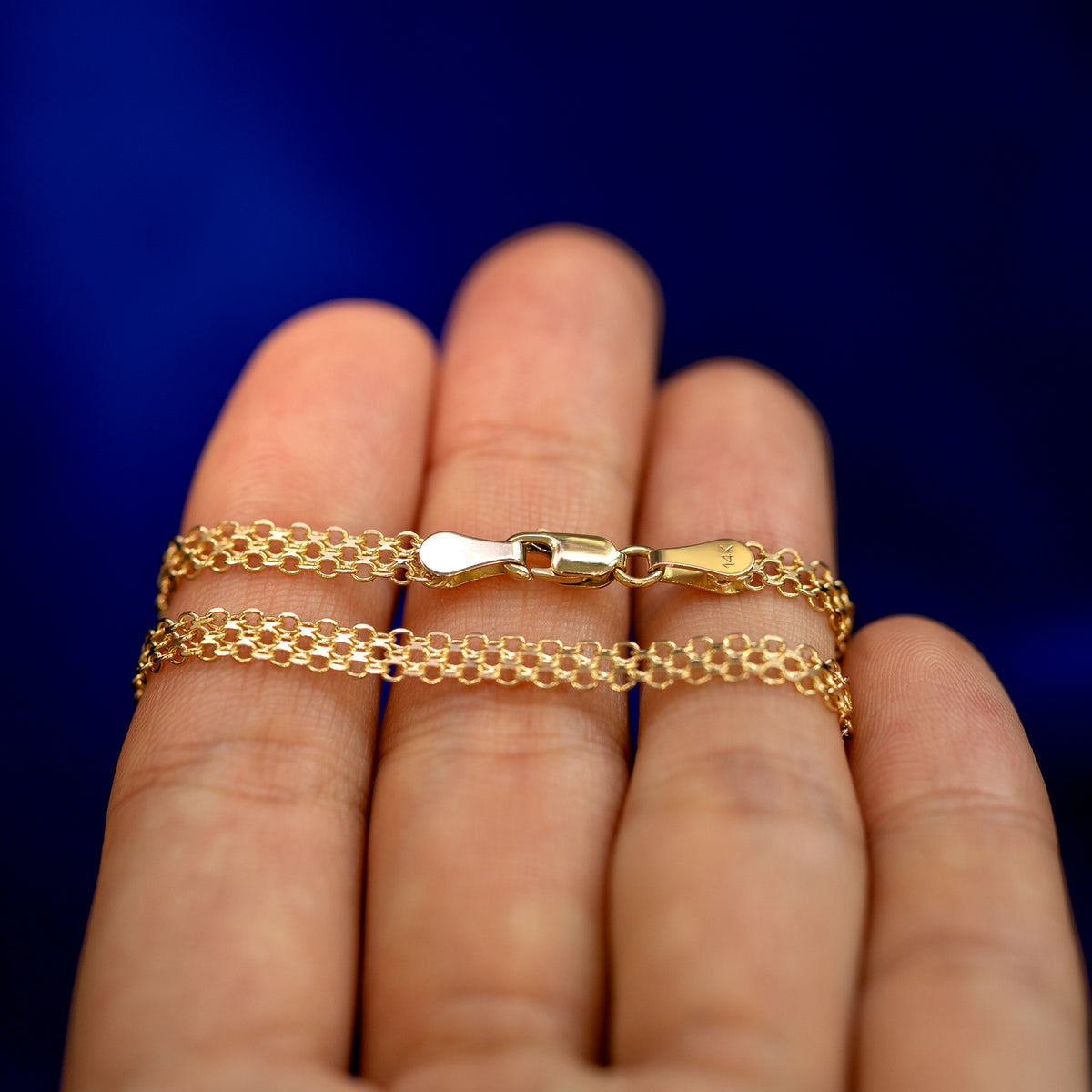 A yellow gold Bismarck Chain wrapped around a model's fingers to show the chain and the lobster claw clasp