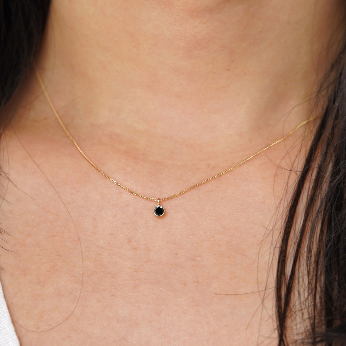 A model's neck wearing a solid 14k yellow gold Black Diamond necklace