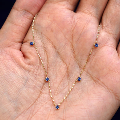 A yellow gold sapphire 5 Gemstone Cable Necklace draped on a model's palm