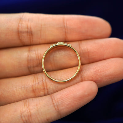 A yellow gold Gemstone Claddagh Band in a model's hand showing the ness of the band