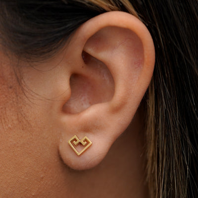 A model's ear wearing a recycled 14k gold Chere Heart Earring