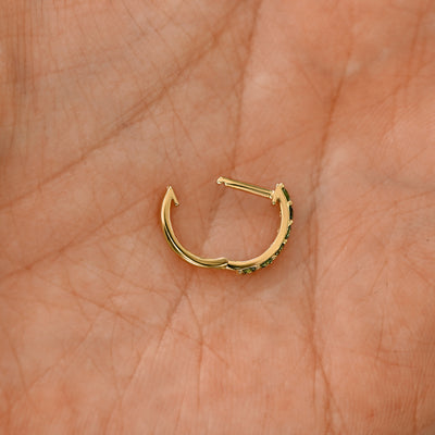 An open lab light green diamond huggie hoop laying in a models palm