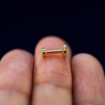 Side view of a yellow gold Large Circle Flatback Piercing on a model's fingertips