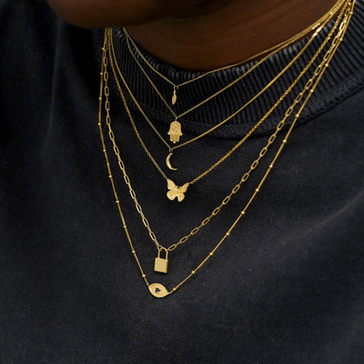 A model wearing seven different yellow gold charm necklaces layered