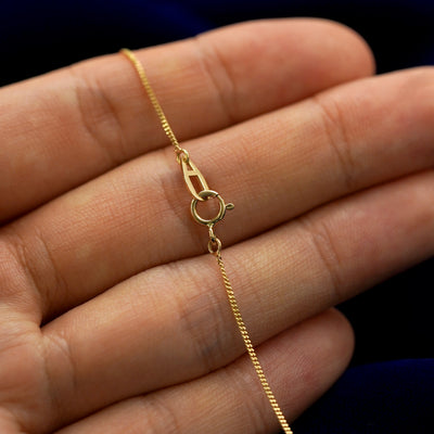 A model holding a mini leaf necklace to show the lobster claw clasp on the essential chain