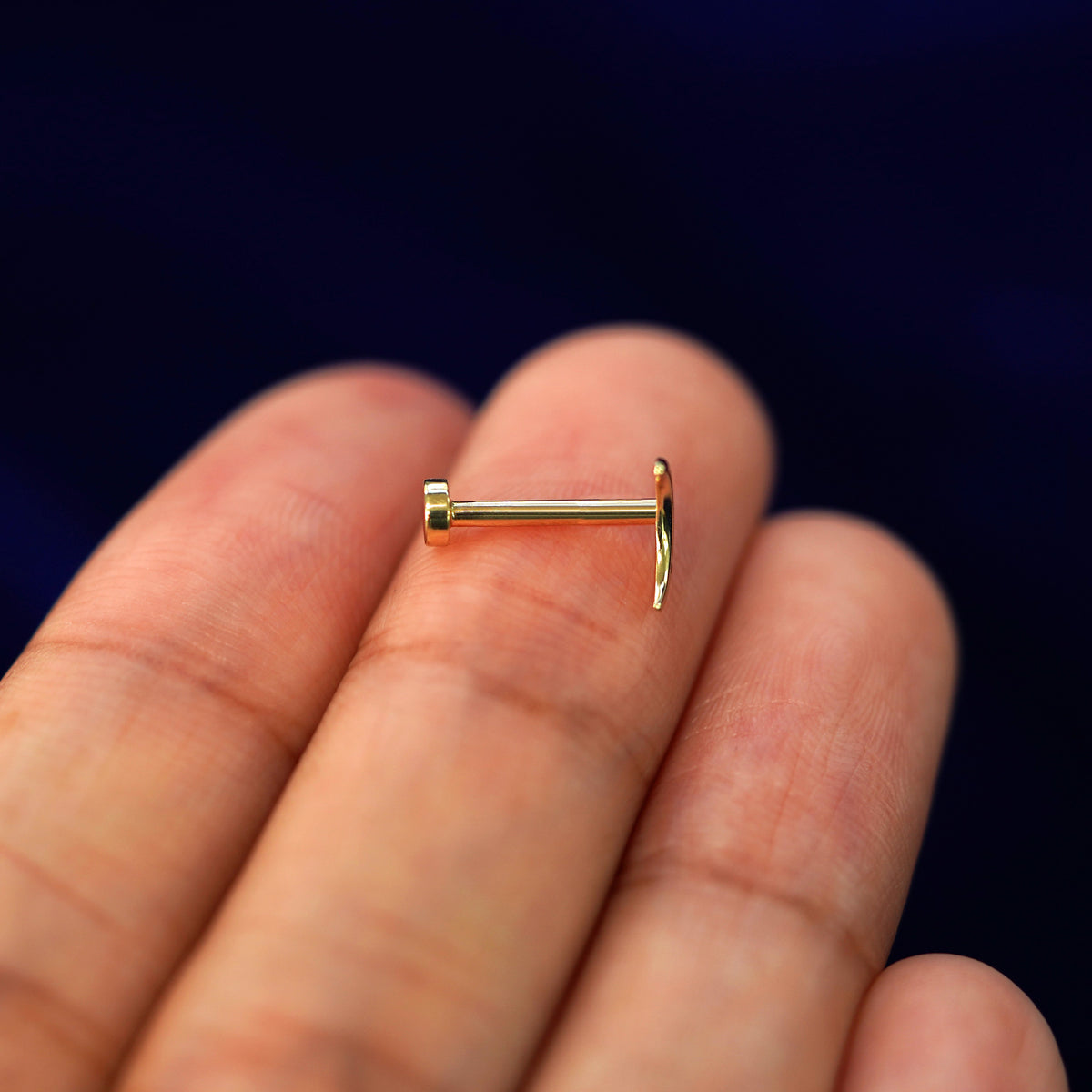 Side view of a yellow gold crescent Moon Flatback Piercing on a model's fingertips