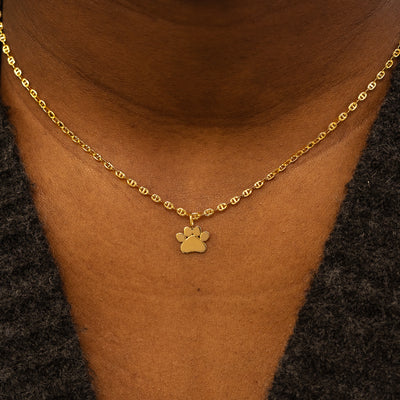 A model wearing a solid gold paw charm on a mariner chain