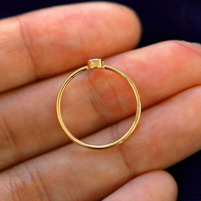 A yellow gold Pink Sapphire Ring in a model's hand showing the thickness of the band