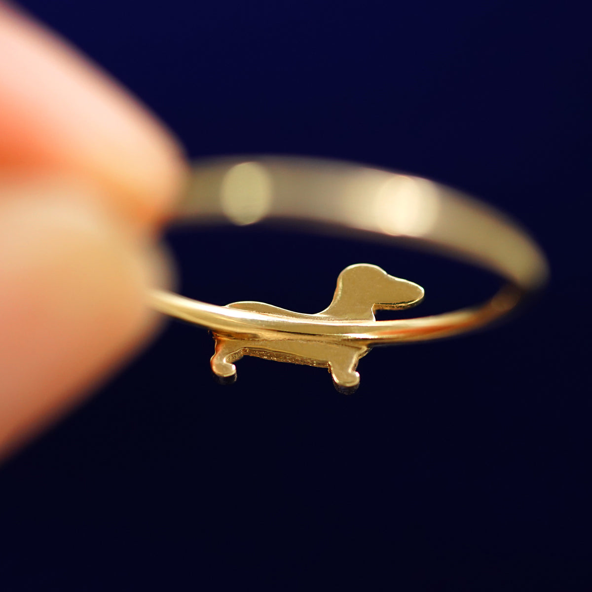 A yellow gold Dog Ring in a model's hand showing the thickness of the band