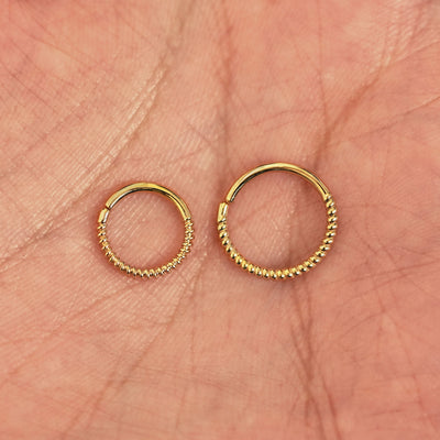 A model's palm holding two versions of the pierced Rope Septum showing the 8mm and 10mm sizes