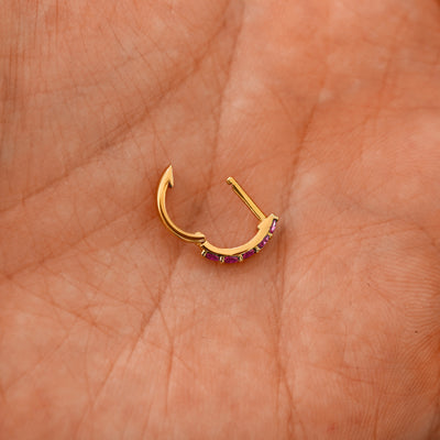 An open Ruby huggie hoop laying in a models palm