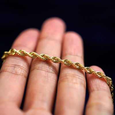 A yellow gold Thick Rope Chain resting on a model's fingers