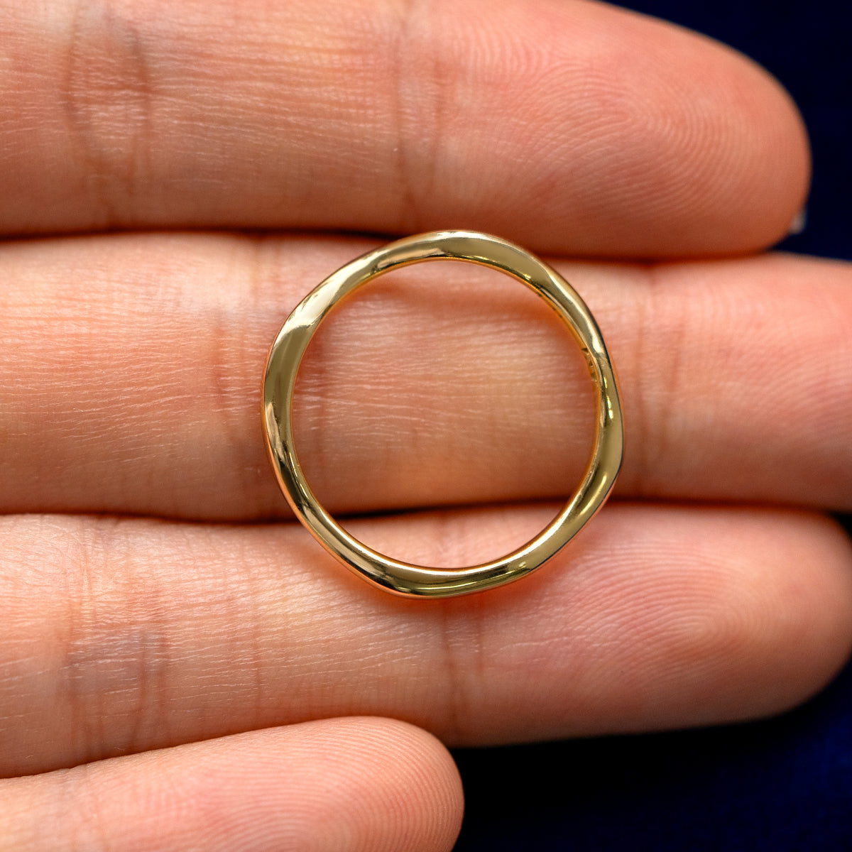 A yellow gold Thin Liquid Band in a model's hand showing the thickness of the band