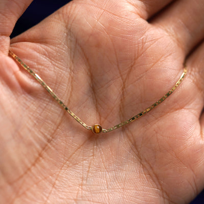 A yellow gold Tiger Eye Bracelet draped on a model's palm