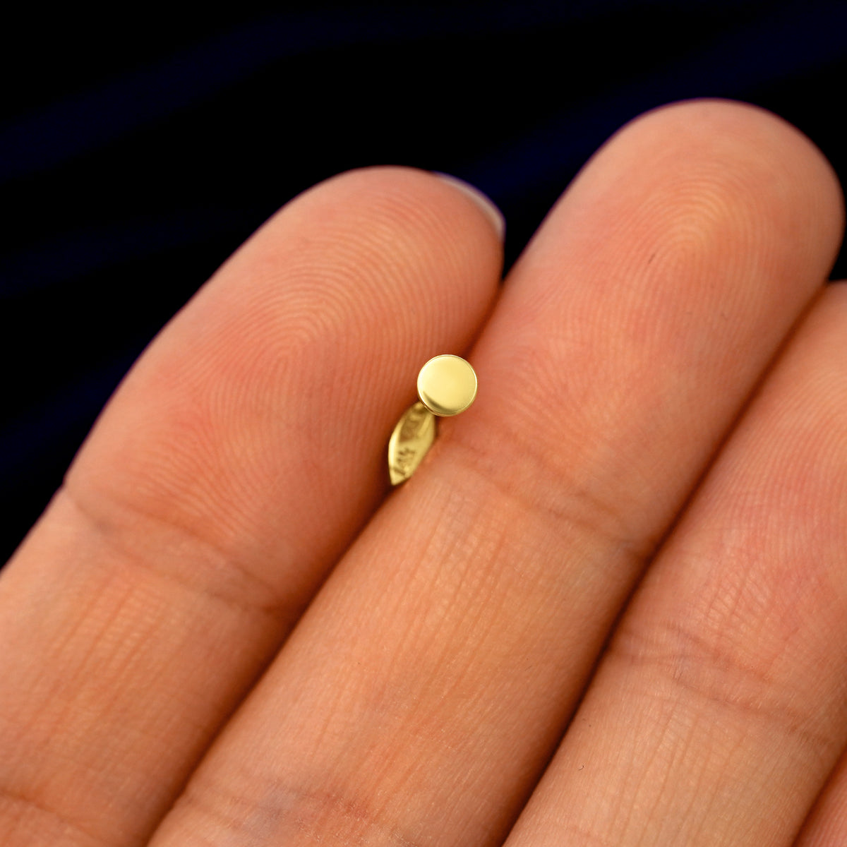 Back view of a solid gold Mini Leaf Flatback Piercing stud held between two fingers
