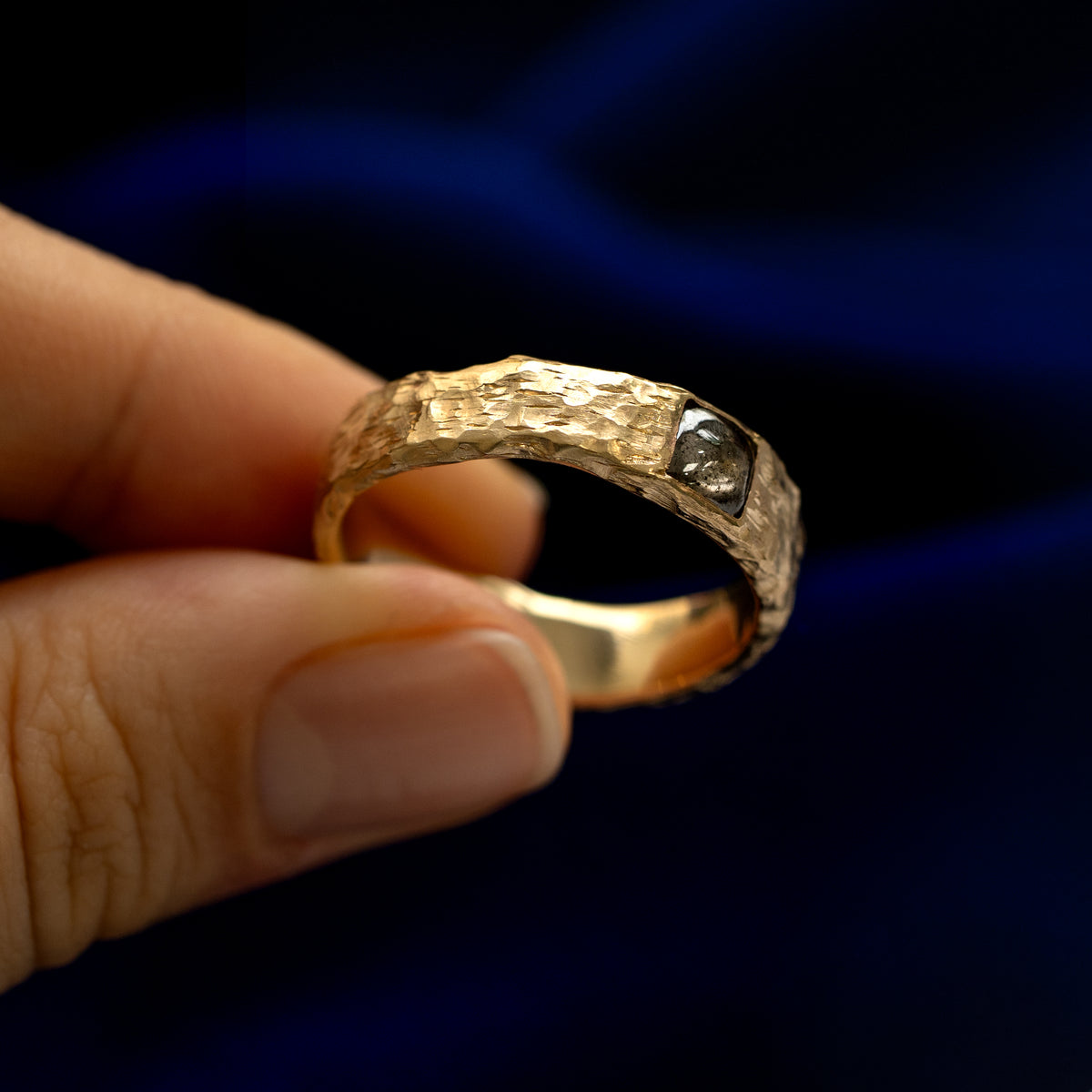 A model holding a square diamond organic band tilted to show the details of the stone and the setting