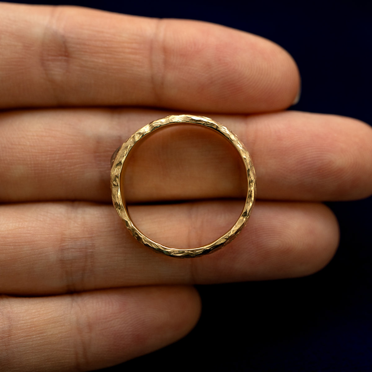 A square diamond organic band laying flat in a models palm to show the thickness of the band