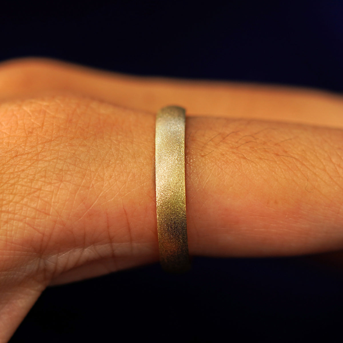 Side view of a Curvy Stardust Band on a model's finger