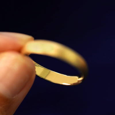 A model holding a Curvy Stardust Band tilted to show the inside of the ring